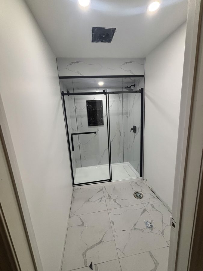 Walk-in shower with marble-look walls and matte black hardware